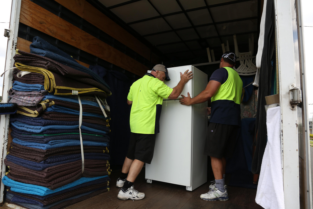 men loading a fridge to a truck