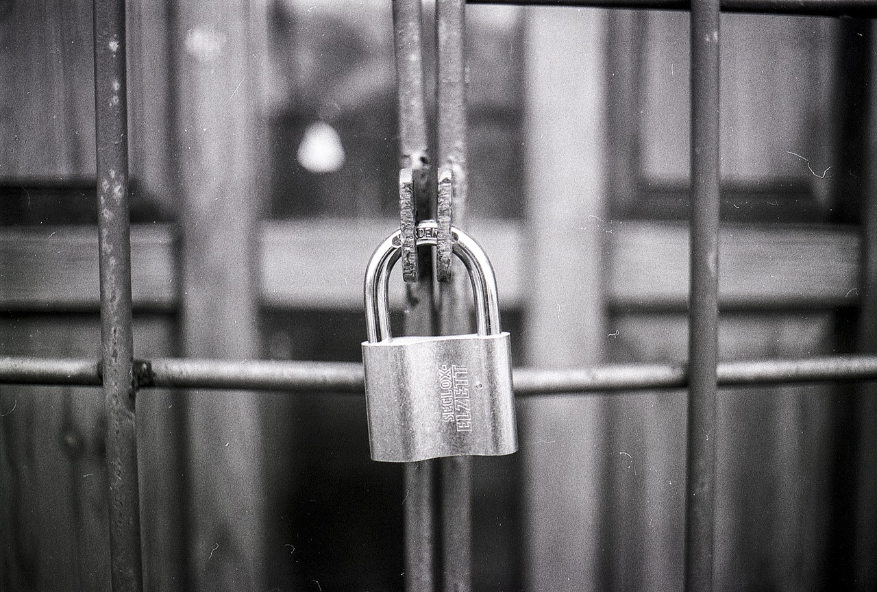 black and white shot of locked metal fence